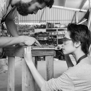 Professional carpenters using tape measure when checking size of stool